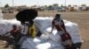 Ethiopian refugees sit on bags of food aid at the Village 8 refugees transit camp, which houses Ethiopian refugees fleeing the fighting in the Tigray region, near the Sudan-Ethiopia border, Dec 2, 2020