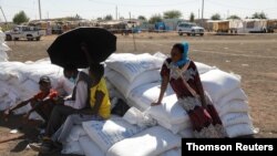 Ethiopian refugees sit on bags of food aid at the Village 8 refugees transit camp, which houses Ethiopian refugees fleeing the fighting in the Tigray region, near the Sudan-Ethiopia border, Dec 2, 2020