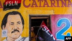 Un hombre sostiene una bandera del Frente Sandinista de Liberación Nacional (FSLN) junto a un mural en Catrina, Nicaragua, que representa al presidente de Nicaragua, Daniel Ortega el 17 de julio de 2020.