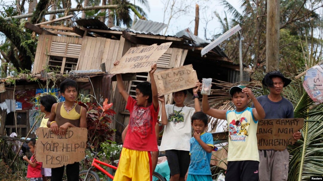 Anak-anak mengusing tanda meminta pertolongan dan makanan di pinggir jalan raya di Tabogo, salah satu kota di provinsi Cebu, Filipina, yang dilanda topan Haiyan.