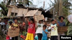 Anak-anak mengusing tanda meminta pertolongan dan makanan di pinggir jalan raya di Tabogo, salah satu kota di provinsi Cebu, Filipina, yang dilanda topan Haiyan.