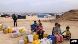 Displaced Palestinian children wait by containers for water supply at their tent camp in Rafah in the southern Gaza Strip on April 26, 2024 amid the ongoing conflict between Israel and the Palestinian militant group Hamas. (Photo by MOHAMMED ABED / AFP)