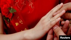 Pengantin pria asal Provinsi Hebei di China, memasang cincin kawin ke jari pengantin perempuan, dalam kawin massal di Seoul, Korea Selatan, 20 September 2006. (Foto: Reuters)