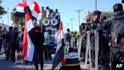 Demonstran mengibarkan bendera Irak dalam aksi protes menentang rencana perubahan aturan pemilu di dekat gedung parlemen di Baghdadm Irak, pada 27 Februari 2023. (Foto: AP/Hadi Mizban)