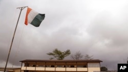 Un drapeau ivoirien flotte devant un bureau de vote d'Abidjan, le 25 octobre 2015.