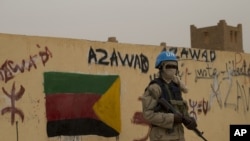 FILE—In this July, 28, 2013 photo, a UN peacekeeper stands guard at the entrance to a polling station covered in graffiti supporting the creation of the independent state of Azawad, in Kidal, Mali. On November 13, 2023, Mali's military announced it had taken the city from rebels.