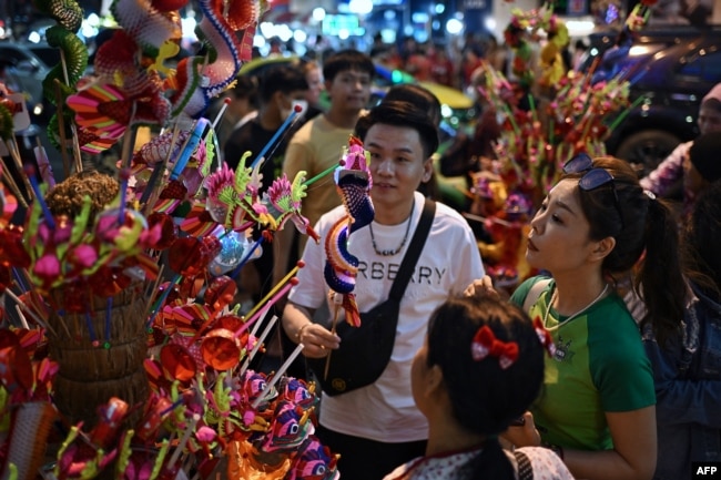 People buy dragon puppets on Yaowarat Road in Bangkok's Chinatown on Feb. 9, 2024, on the eve of the Lunar New Year.