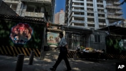 Seorang pria berjalan melewati penjual buah yang sedang menunggu pelanggan di luar lokasi pembangunan perumahan mewah di Beijing, Selasa, 24 September 2024. (Andy Wong/AP)