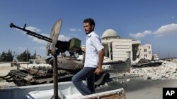 A Free Syrian Army soldier drives by a Syrian tank and a mosque, which were destroyed during fighting with government forces, in Azaz, on the outskirts of Aleppo, Sept. 23, 2012. 