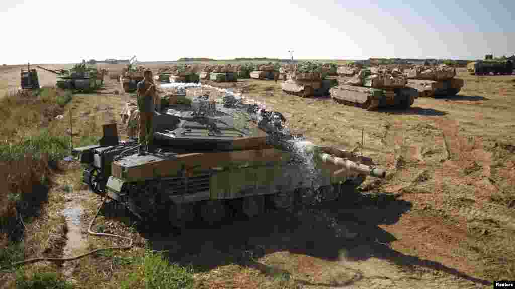 An Israeli soldier washes a tank at a staging area near the border with the Gaza Strip, Aug. 10, 2014. 