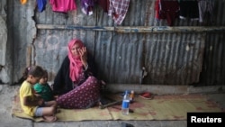 A Palestinian woman sits with her grandchildren in Khan Younis refugee camp in the southern Gaza Strip, July 11, 2017. 