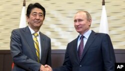 Presiden Rusia Vladimir Putin (kanan) berjabat tangan dengan PM Jepang Shinzo Abe di Sochi, Rusia (6/5).