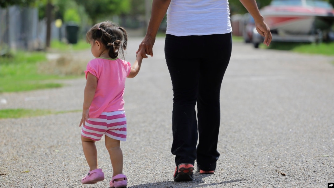 FILE - In this Sept. 16, 2015, photo, a woman in Sullivan City, Texas, who says she entered the country illegally, walks with her daughter, who was born in the U.S. A federal judge on Feb. 5, 2025, paused an executive order trying to end birthright citizenship.