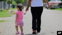 FILE - In this Sept. 16, 2015, photo, a woman in Sullivan City, Texas, who says she entered the country illegally, walks with her daughter, who was born in the U.S. A federal judge on Feb. 5, 2025, paused an executive order trying to end birthright citizenship.