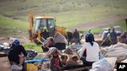 FILE - Palestinian Bedouin watch Israeli troops demolish tents and other structures of the Khirbet Humsu hamlet in Jordan Valley in the West Bank, Feb. 3, 2021.