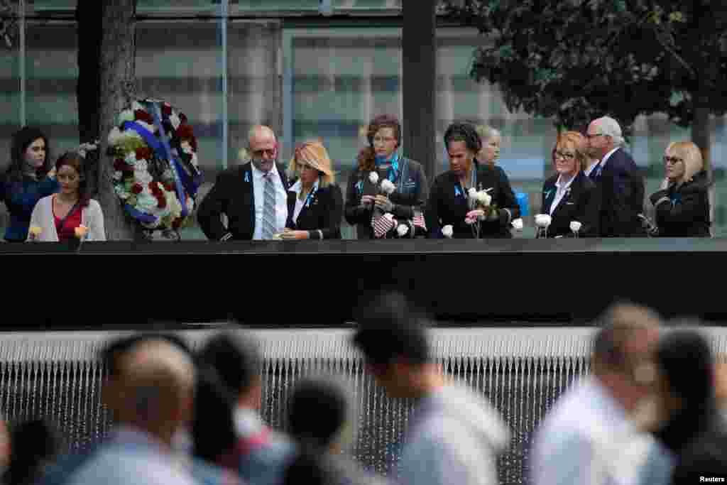 Airline employees visit the north reflecting pool during ceremonies at the 911 Memorial in lower Manhattan, New York, Sept. 11, 2019.