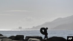 Edward Murat, de 20 años, carga su cámara neumática en Playa Escondida en La Guaira, Venezuela, para ir a pescar. 14 de agosto de 2020.