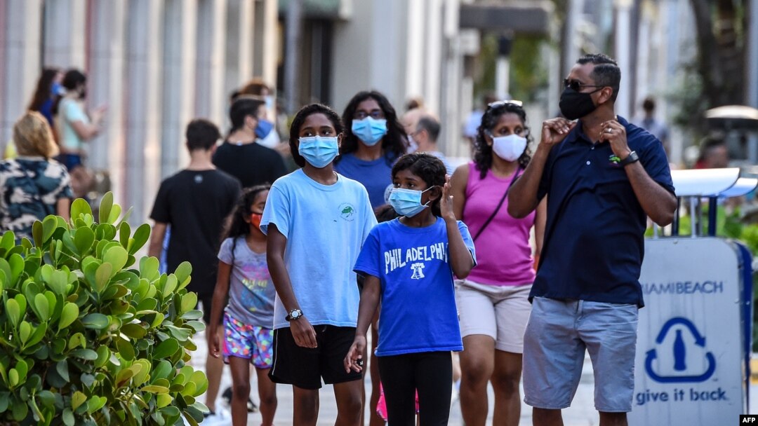 Satu keluarga mengenakan masker saat berjalan-jalan di Miami Beach, Florida, 29 Juni 2020.