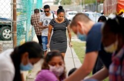 FILE - Maria de Jesus Ruiz Carrasco, center, from Cuba and seeking asylum in the U.S., uses crutches as she arrives at a clinic in Matamoros, Mexico, to have her broken leg bandages changed.