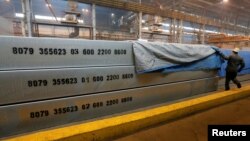 An employee removes a covering of 13-meter aluminium ingots weighing 34 tons (74,957 pounds) at the foundry shop of the Rusal Krasnoyarsk aluminium smelter in Krasnoyarsk, Siberia, July 27, 2016. 