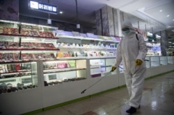 A health worker sprays disinfectant inside the Pyongyang Department Store No. 1 prior to opening for business, in Pyongyang on Dec. 28, 2020.