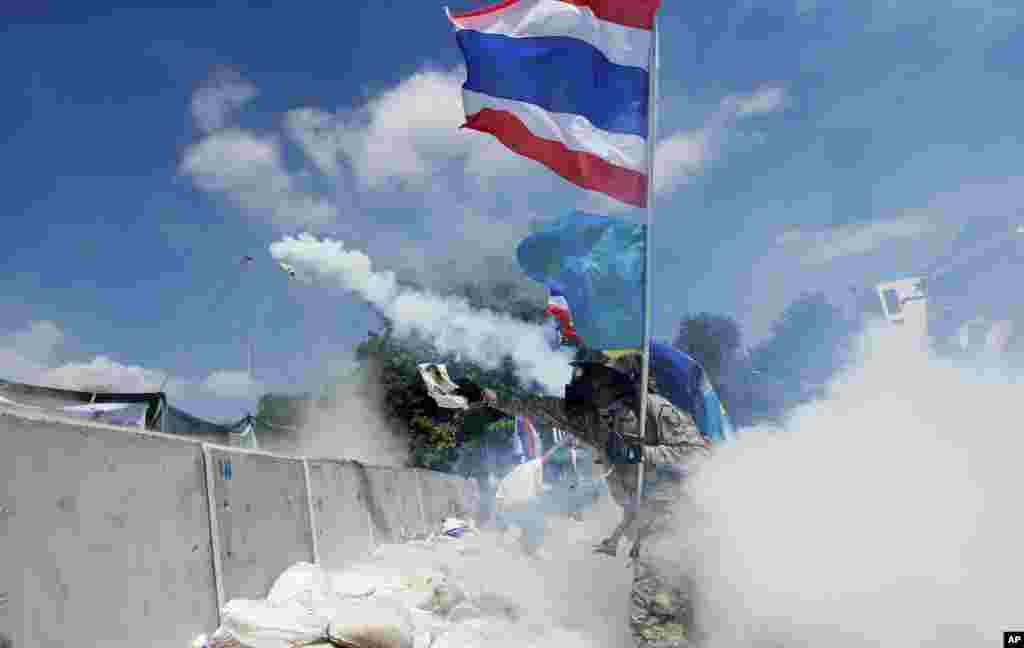 An anti-government protester throws back a tear gas canister fired by riot police in Bangkok, Thailand, Dec. 1, 2013.