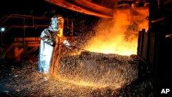 A worker in a protective suit pokes a metal rod to tap slag from a smelting furnace at PT Vale Indonesia's nickel processing plant in Sorowako, South Sulawesi, Indonesia, Tuesday, Sept. 12, 2023.