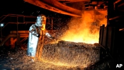 FILE - A worker in a protective suit pokes a metal rod to tap slag from a smelting furnace at PT Vale Indonesia's nickel processing plant in Sorowako, South Sulawesi, Indonesia, Sept. 12, 2023. 