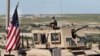 FILE - A U.S. soldier sits atop an armored vehicle, in Manbij, Syria, April 4, 2018. 