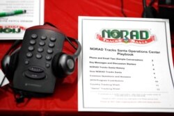 FILE - A staffer's playbook and phone are seen in this Dec. 23, 2019, photo taken at NORAD's Santa tracking center in Colorado Springs, Colo.
