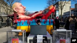FILE — Mock voting boxes with shredded ballots and a model of Russian President Vladimir Putin is displayed at a protest near the polling station at the Russian embassy in Berlin, after noon local time, March 17, 2024.