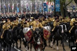 Las tropas acompañan al rey Carlos III de Gran Bretaña y Camilla, la reina consorte, cuando llegan en el carruaje desde el Palacio de Buckingham hasta la Abadía de Westminster para su ceremonia de coronación, en Londres, el sábado 6 de mayo de 2023. (Foto AP/Kin Cheung)