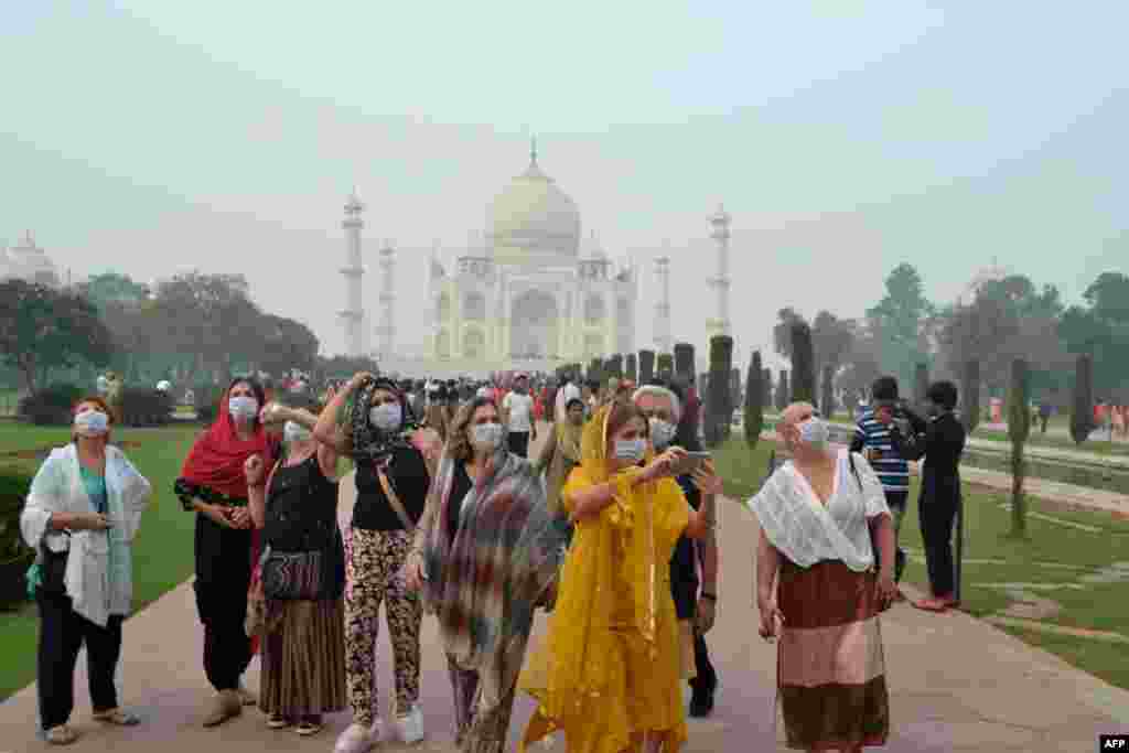 Foreign tourists wearing face masks visit the Taj Mahal under heavy smog conditions, in Agra, India. 