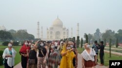 Foreign tourists wearing face masks visit the Taj Mahal under heavy smog conditions, in Agra, India. 