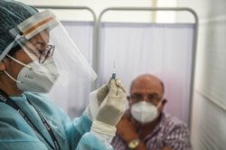 FILE - A health worker prepares a syringe to inoculate a volunteer with a COVID-19 vaccine produced by China's Sinopharm during its trial at the Clinical Studies Center of the Cayetano Heredia University in Lima, Dec. 9, 2020.