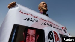 FILE - A man whose relatives were killed during the 2011 Egyptian revolution holds a banner with pictures of former President Hosni Mubarak, Sept. 27, 2014.