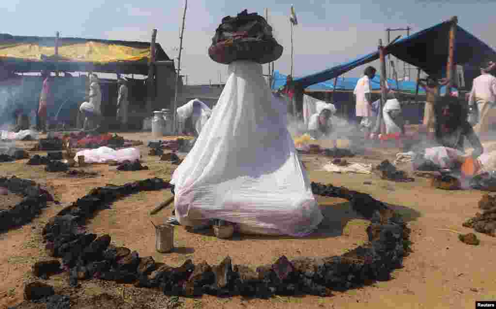 Sadhus or Hindu holy men offer prayers while sitting inside circles of burning &quot;Upale&quot; (or dried cow dung cakes) after taking a dip during the third &quot;Shahi Snan&quot; (grand bath) at &quot;Kumbh Mela&quot; or the Pitcher Festival, in Prayagraj, previously known as Allahabad, India.