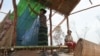 A Cambodian woman hangs her mosquito net in the temporary dwelling in the fields that she and her husband are clearing to farm.