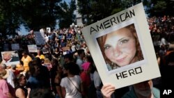 FILE - A protester holds up a photo of Heather Heyer at a "Free Speech" rally in Boston, Massachusetts. Heyer was killed when a car, driven by James Alex Fields Jr., plowed into a group of people during protests Charlottesville, Virginia.