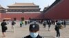 A security guard stands watch as people line up while ensuring social distancing, to enter the Forbidden City, the former palace of China&#39;s emperors, in Beijing. The area was reopened three months after it closed due to the coronavirus crisis.