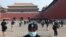 A security guard stands watch as people line up while ensuring social distancing, to enter the Forbidden City, the former palace of China's emperors, in Beijing. The area was reopened three months after it closed due to the coronavirus crisis.