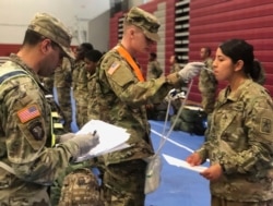 In this image provided by the U.S. Army, recent Army basic combat training graduates have their temperatures taken as they arrive at Fort Lee, Va, on March 31, 2020, after being transported using sterilized buses from Fort Jackson, S.C.