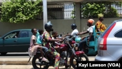 Un conducteur de moto remorquant 3 passagers à Lomé, le 14 août 2019. (VOA/Kayi Lawson)