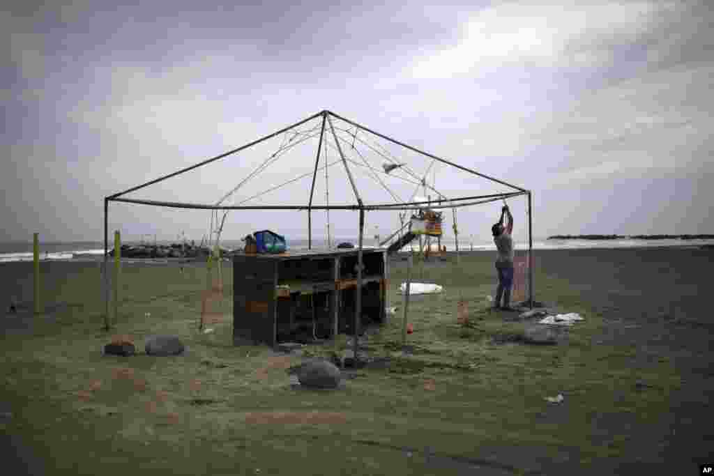 Una mujer amarra la estructura de un negocio de playa mientras se prepara para la llegada del huracán Franklin, en el puerto de Veracruz, México. Agosto 9, 2017. 