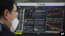 A screen shows a news report about US President Joe Biden's inauguration as a currency trader works at the foreign exchange dealing room of the KEB Hana Bank headquarters in Seoul, South Korea, Jan. 21, 2021.