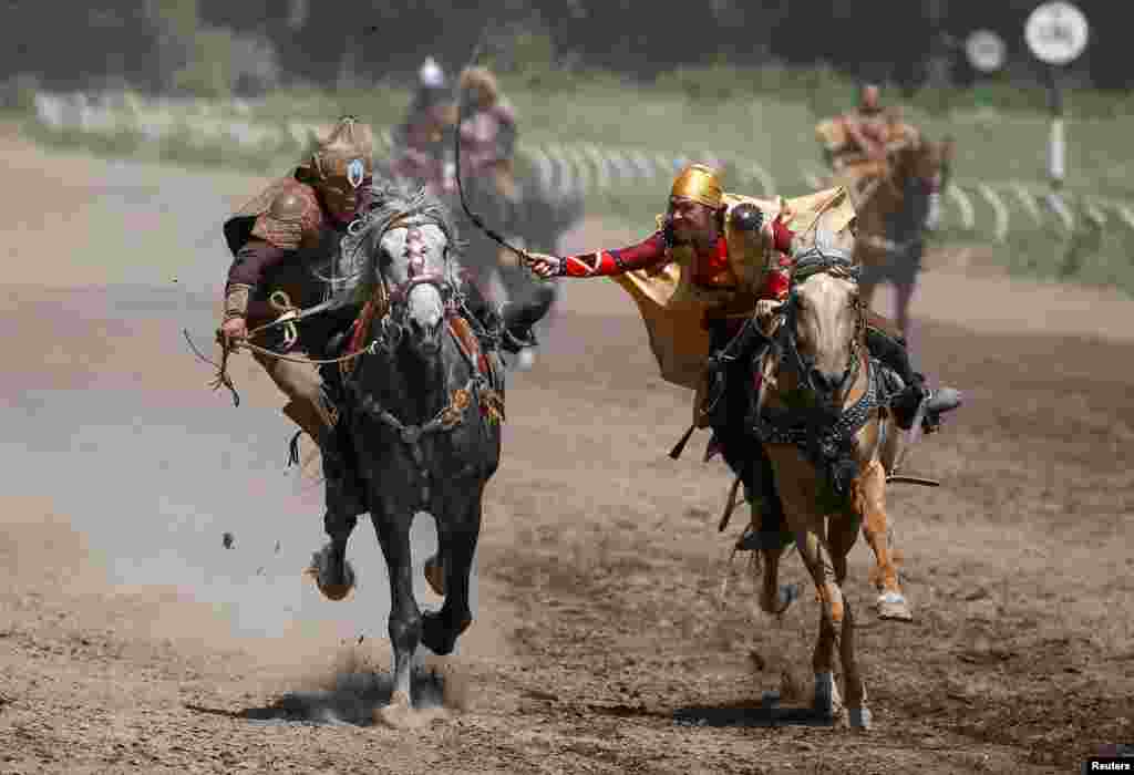 Riders of Nomad Stunts group perform the Kyz Kuu (catch the girl) national riding game, where a girl whips a male contestant as she defends herself, during a show in Almaty, Kazakhstan.