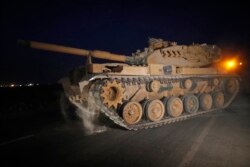 FILE - A Turkish army tank is driven to its new position on the Turkish side of the border between Turkey and Syria, in Sanliurfa province, southeastern Turkey, Oct. 8, 2019.