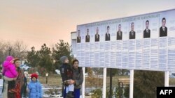 Residents look at a presidential election poster depicting the candidates in Ashgabat, Turkmenistan, February 7, 2012.