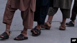 FILE - Recaptured Afghan prisoners walk in leg chains in jail in Kandahar, Afghanistan, April 26, 2011.