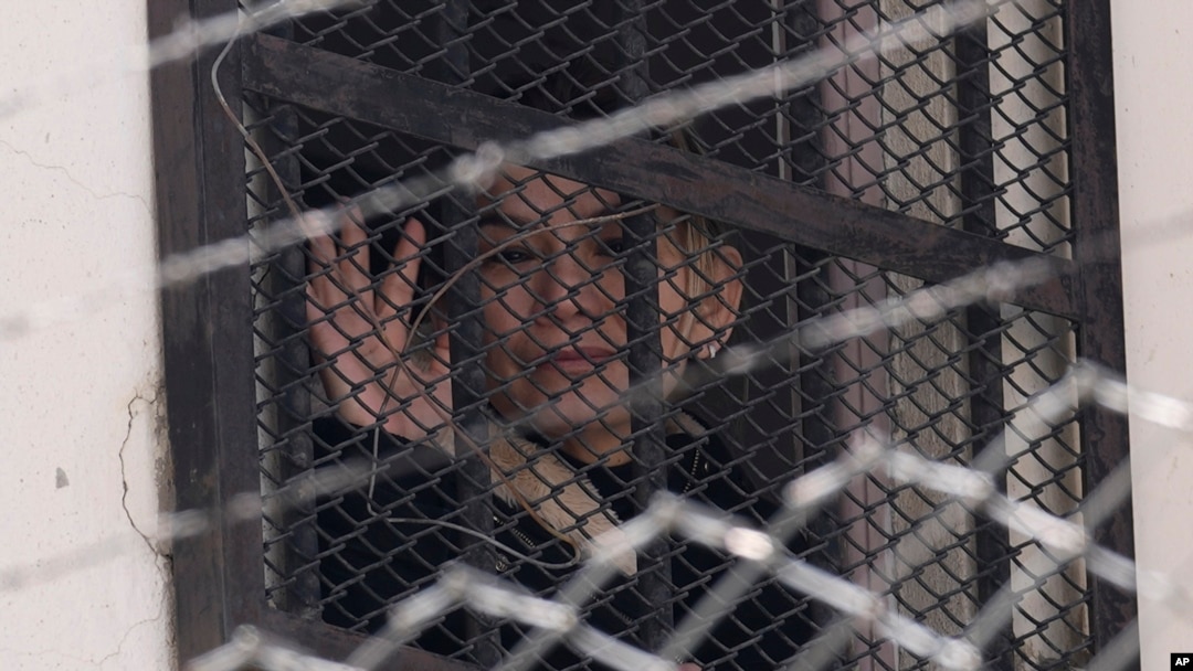 La expresidenta interina de Bolivia, Jeanine Áñez, saluda desde una ventana de la cárcel de mujeres de Miraflores a sus partidarios que protestan por su liberación en La Paz, Bolivia, el miércoles 18 de agosto de 2021.